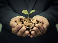 Man holding coins with plant growth